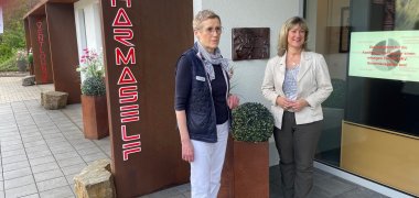 Apothekerin Frau Porten-Bergmann und Landrätin Frau Beilstein stehen vor der Kreuzberg-Apotheke.