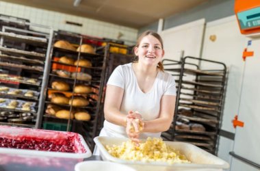 Man sieht eine Angestellte der Bäckerei Müsch beim Teig Kneten.