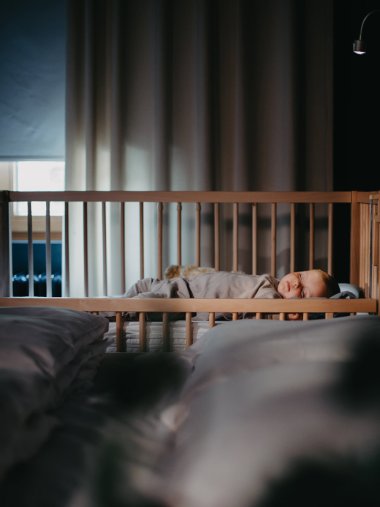 Ein Kind liegt in einem tiSsi-Kinderbett