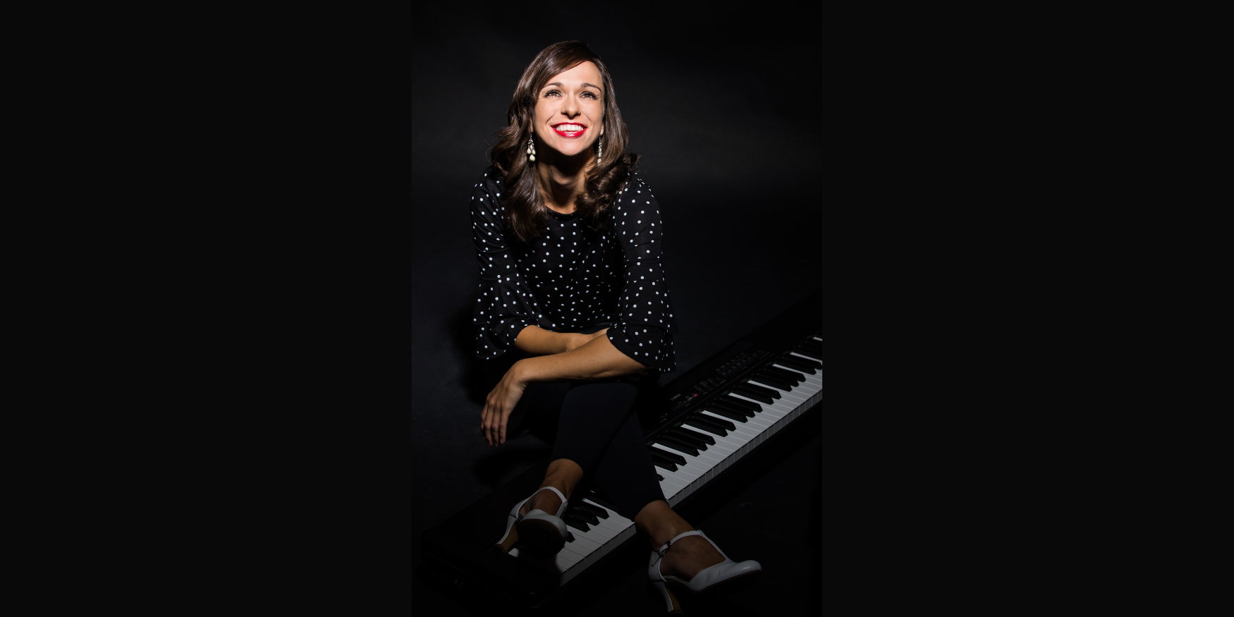 Anna Piechotta mit Klavier Anna Piechotta sitzt lachend auf einem Klavier.