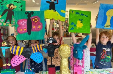Kinder präsentieren ihre Kunstwerke, die sie im Rahmen eines Kurses der JUKUSCH gemacht haben.