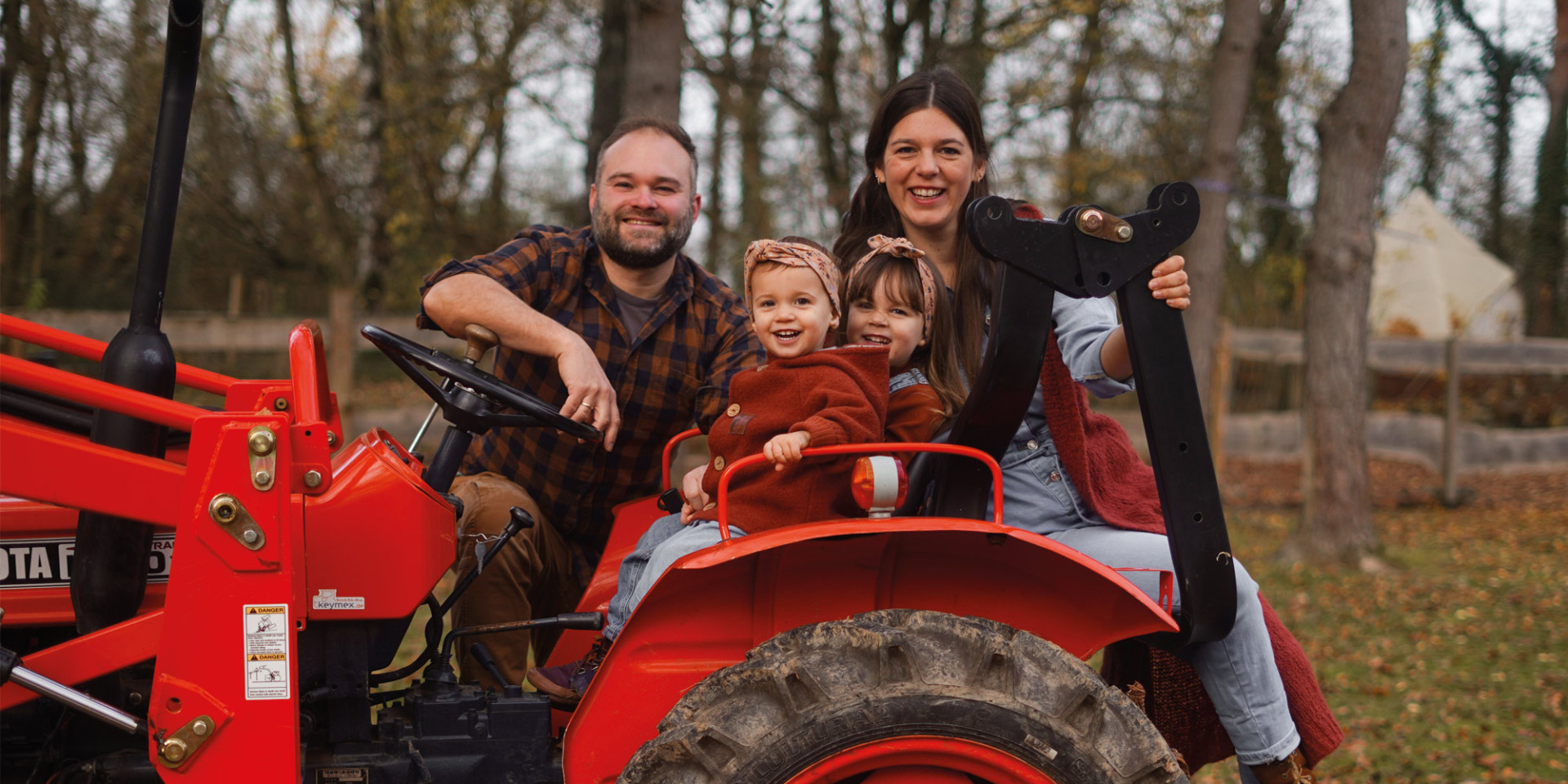 Familienfoto von Carmen und Mätty (Naturerlebnishof Vulkaneifel) auf einem Traktor