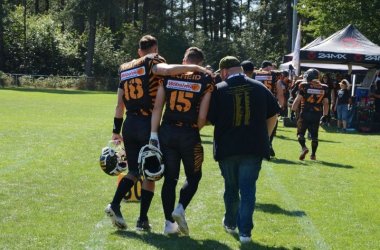 Zwei Spieler und Vorsitzender Sebastian gehen vom Spielfeld dabei haben sie sich jeweils in den Armen.