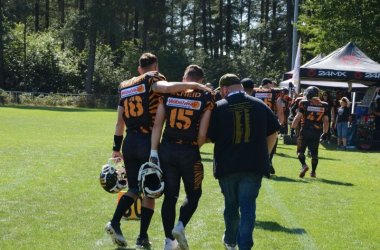 Vorsitzender Sebastian und zwei Spieler gehen Arm in Arm vom platz.