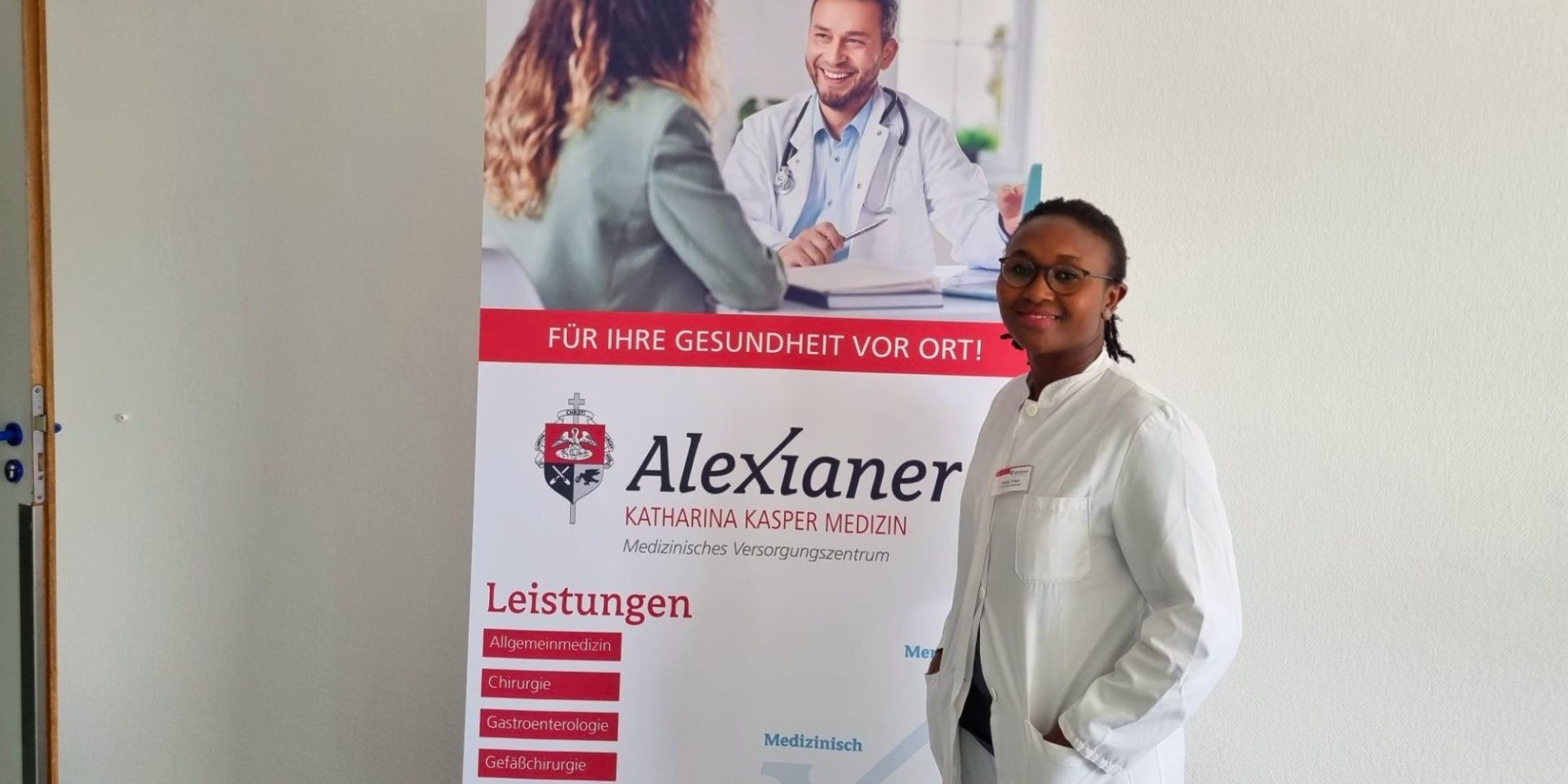 DR. Yemen lächelt in die Kamera und steht neben einem Schild.