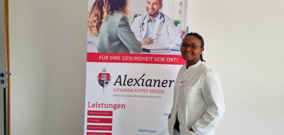 Dr. Ymen, HNO DR. Yemen lächelt in die Kamera und steht neben einem Schild.