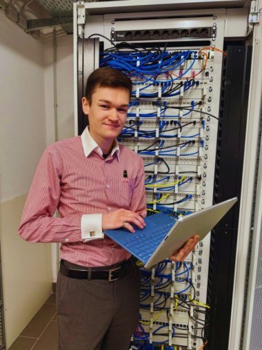 Luca Rohmann absolviert die Ausbildung zum Fachinformatiker für Systemintegration. Auf dem Bild steht er da mit Laptop in der Hand.