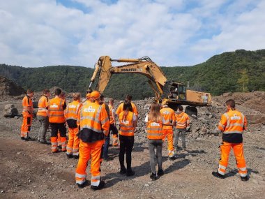 Viele Mitarbeterinnen und Mitarbeter von Schnorpfeil auf einer Baustelle in neon-orangener Montur.