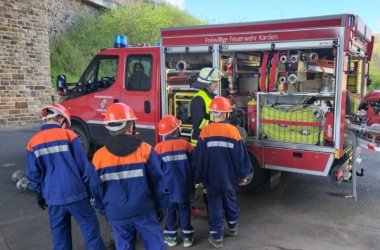 Die Jugendfeuerwehr steht in passender Feuerwehrkleidung am Feuerwehrauto.