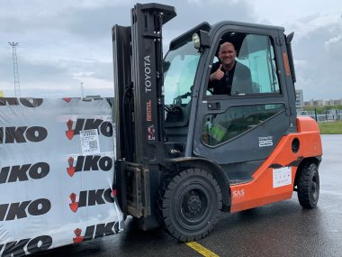 Gabelstaplerfahrer von IKO Insulations zeigt einen Daumen nach oben bei der Arbeit.