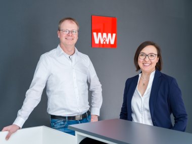 Sascha und Susanne Johann stehen in ihrer Agentur vor dem Logo der Württembergischen Versicherung