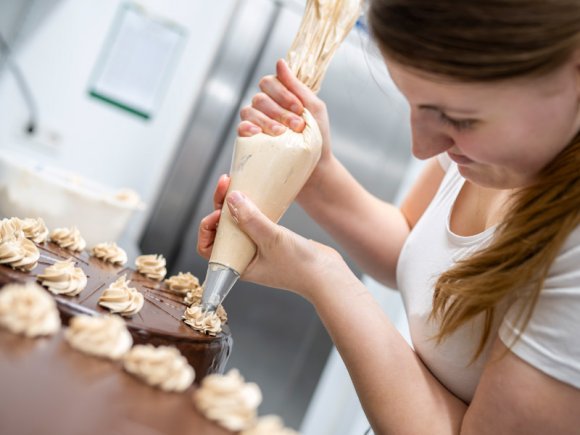 Bäckerei Müsch - Mitarbeiterin beim Tortenverzieren Eine Mitarbeiterin der Bäckerei Müsch verziert eine Torte in der Backstube.