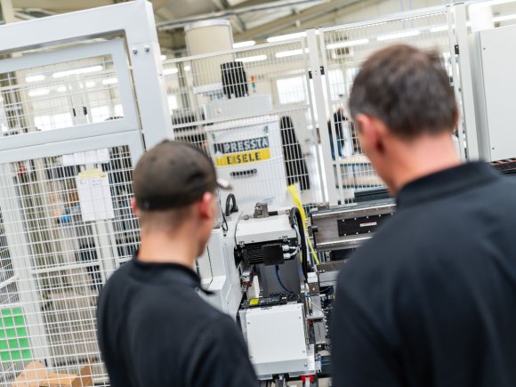 Marvin und Andre vor einer Maschine Marvin und Andre schauen sich eine Anlage in der Produktion der Firma Pressta-Eisele an