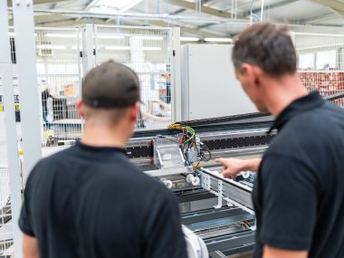 Pressta-Mitarbeiter stehen vor einer Maschine