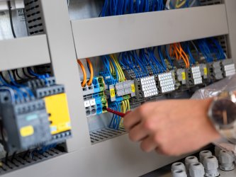 Die Hand eines Mitarbeiters beim Einstellen der Technik einer Produktionsanlage