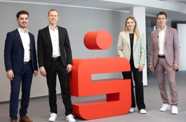 Azubi Admir, Jan Eric Schütze, Azubine Mina und Frank Michels stehen am Sparkassenlogo