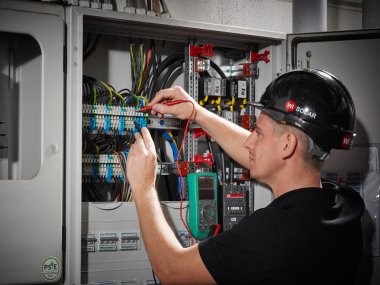 Ein Mitarbeiter von Wi SOLAR bei der Arbeit an einem Kabelschrank