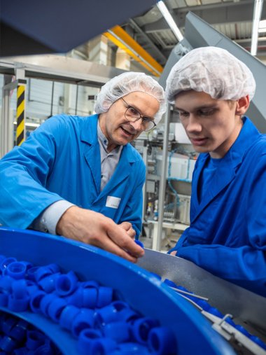 Betriebsleiter und Azubi an einer Produktionsanlage von Verschlüssen bei Zeller Plastik