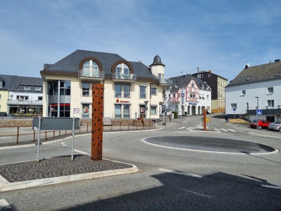 Man sieht eine zentrale Kreuzung mit Kreisel in Kaisersesch, im Hintergrund die Sparkasse.