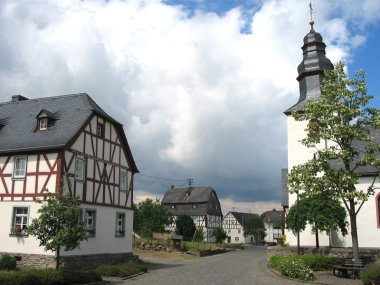 Die Dorfmitte von Altstrimmig im Hunsrück mit Kirche und Fachwerkhäusern.